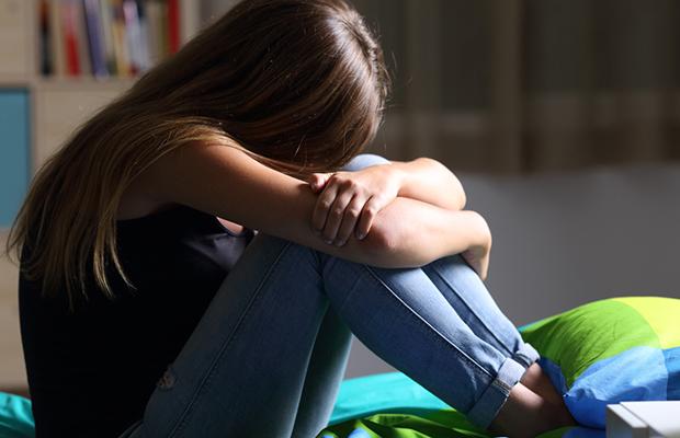 young girl hugging her knees with her head on her knees